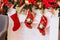 Bright colorful red socks for Santa Claus gifts hanging on the white fireplace with holiday decorations. Traditional Christmas