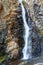 Bright colorful, very high mountain waterfall with mineral iron water falling from the rock