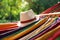 Bright comfortable hammock with hat hanging in garden, closeup