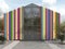 A bright commercial public building or pavilion with a pitched roof. Modern creative colorful facade with a glass entrance group