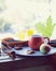 Bright cup with coffee on a window background, apples on a plate, warm scarf, leaves