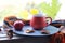 Bright cup with coffee on a window background, apples on a plate, warm scarf, leaves