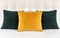 Bright decorative soft pillows in bed on the background of leather quilted headboard. Emerald and orange pillow, part of bed close