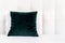 Bright decorative soft pillows in bed on the background of leather quilted headboard. Emerald and orange pillow, part of bed close