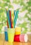 Bright disposable paper cups and straws on abstract green.