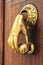 Bright doorknocker with hand shape on old wooden door