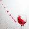 Bright drops of red wine flying out of a glass on a gray abstract background