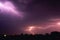 Bright flash of lightning illuminated the night sky and dyed clouds in a blue violet color