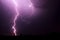 Bright flash of lightning illuminated the night sky and dyed clouds in a blue violet color