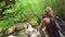 Bright and fresh green nature in Martvili canyon, girl with blond braided hair stands on edge, professional photographer