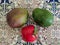 Bright fruits lie on a beautiful ceramic tile. Green mango and red pomegranate lie next to each other. Close-up