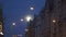 Bright full moon visible in the city streets using tele photo lens with city lights in the foreground and Riga typical