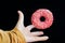 Bright glazed donut and hand grabbing it in motion on a dark background