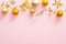 Bright glittering golden baubles, ribbon. stylish Christmas decorations top borer on pastel pink background. Christmas minimal