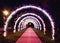 Bright glowing arch of colored lanterns in the park in the evening