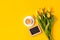 Bright good morning concept - cup of coffee, frame with copyspace, yellow tulips on yellow background, greeting card, seasonal