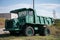 Bright green dump truck with funny eyes parked in a field under a cloudy sky