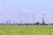 Bright green field with corn and Oil Refinery