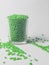 bright green masterbatch, in a glass cup on a white background. This polymer is a colorant in plastic industry products