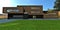 A bright green meadow in front of a chic country estate made of old crane bricks. Stylish designer porch and garage entrance with