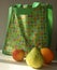 Bright green shopping bag with multicoloured funky floral pattern on the front and fruit in the foreground