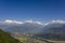 Bright green slope of a hill against the backdrop of the city in a mountain valley and the snowy ridge of Annapurna under a clear