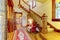 Bright hallway with colourful rug, nice red sofa, wooden staircase and beige carpet covered steps