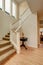 Bright hallway in creamy tones with hardwood floor and staircase
