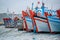 Bright hulls of wooden fishing boats in a row, anchored in the harbor