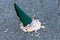 Bright ice cream in a green cone fell on the asphalt. Side view. Close-up.