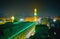 The bright illumination of minaret and walls of Al-Hussain Mosque, surrounded by dark quarters of evening Islamic Cairo district,