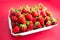 Bright juicy selected strawberries in a portioned cardboard box.