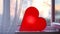 Bright lamp in shape of heart is on window. Concept. Red heart-shaped lamp stands at window and glows to bestow love on