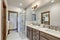 Bright large bathroom interior with glass wakl in shower, two sinks and white quarts countertop