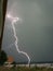 A bright lightning bolt strikes very close to a few greenhouses in Romania