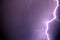 Bright lightning discharges in the stormy sky under dark violet rain clouds