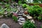 Bright limestone staircase on a rock in the garden. steps of rough stones to a hill with flowers. pink red flowers around the path