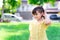 A bright little child girl is walking in a green lawn near the house. The children collected white flowers to wear her ears.