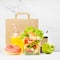 Bright lunch set of seafood shrimp salad in pack, orange juice, coffee cup, donut, packet in white interior with marble tile.