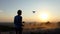 Bright man controls a brand new quadracopter at sunset in slo-mo