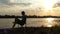 Bright Man Sits on a Folding Chair on The Riverbank, Writes at Sunset