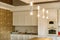 Bright modern cylinder illuminators hanging from the ceiling. Kitchen room on the background