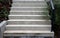 Bright monolithic concrete park staircase with stair lighting with metal railing black interlocking paving, bushes slope