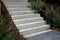 Bright monolithic concrete park staircase with stair lighting with metal railing black interlocking paving, bushes slope