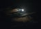 Bright moon illuminates the clouds in the night sky in Barcelona, Spain