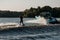 Bright motor boat pulls an active man riding a wakeboard down the river