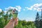 Bright multi-colored ice cream in hand against background of clear blue summer sky and green trees. Highly raised female hand