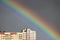 Bright multi-colored wide colorful rainbow after the storm in the gray sky above the town houses