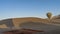 A bright multicolored balloon rises into the blue sky over the desert.