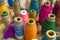 Bright multicolored spools of thread close-up stand on a  table surface against a blurred background